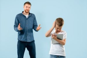 Angry father scolding his son in living room at home