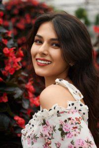 Smiling beautiful brunette woman posing near flowers.